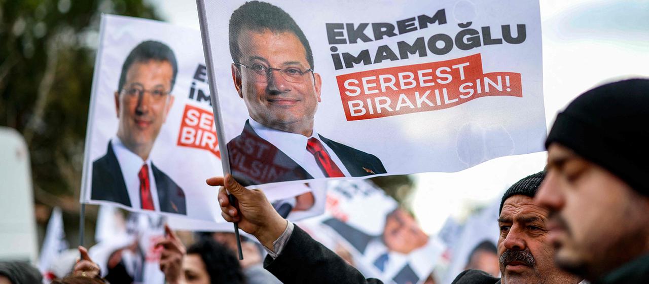 Anhänger von Ekrem İmamoğlu halten Fahnen mit seinem Konterfei in den Händen.