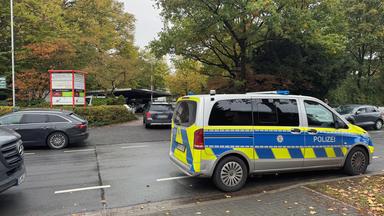 Polizeiauto und andere Autos stehen vor einer Berufssschule in Paderborn.