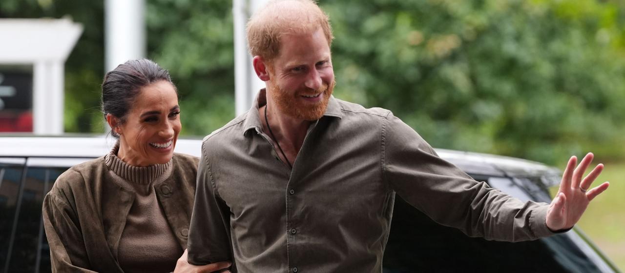 Prinz Harry winkt bei einem Besuch in Melbourne, an seiner Seite seine Frau Meghan.