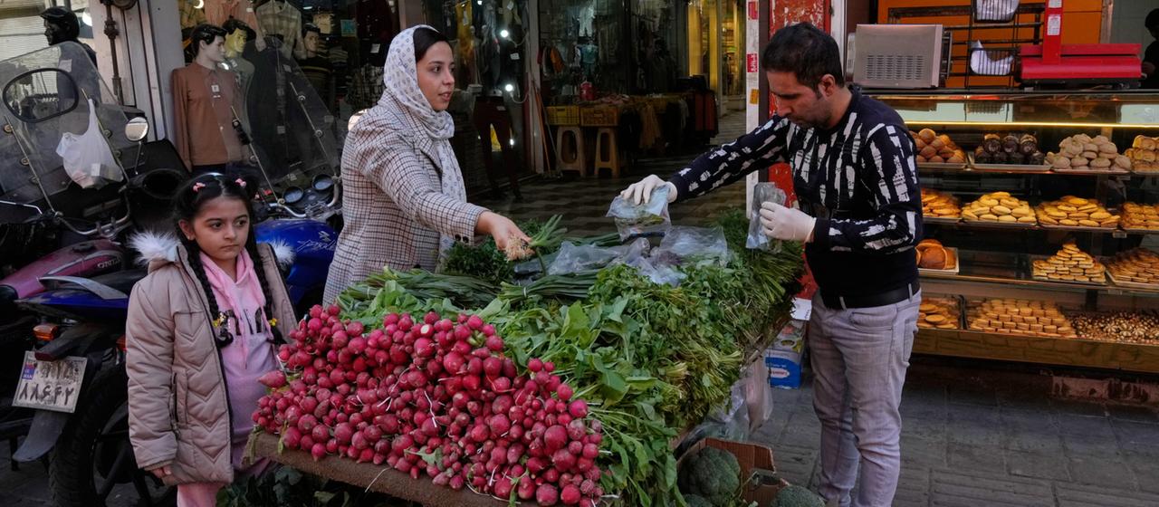 Eine Kundin in Irans Hauptstadt Teheran kauft Gemüse an einem Stand.