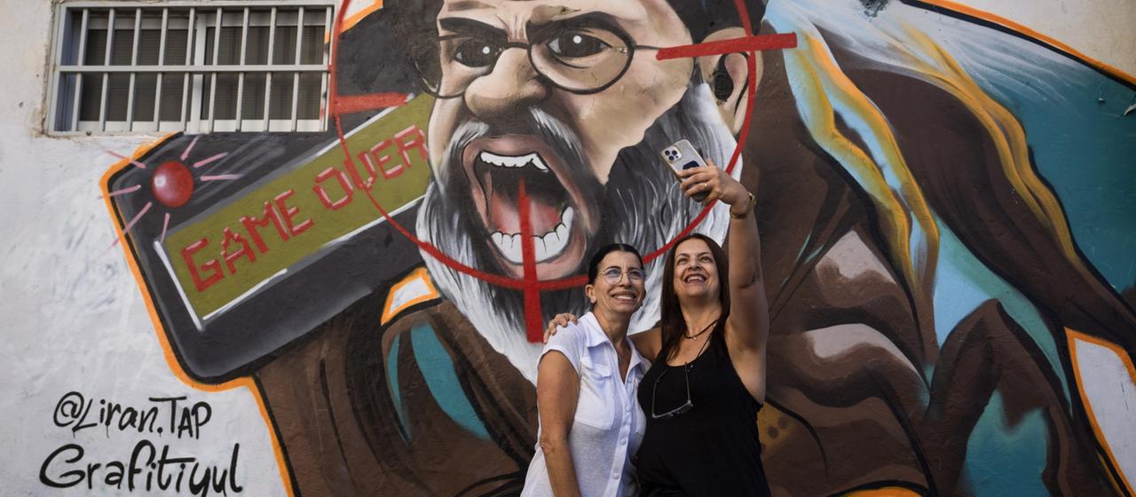 Frauen machen ein Selfie vor einem Nasrallah-Graffiti in Tel Aviv