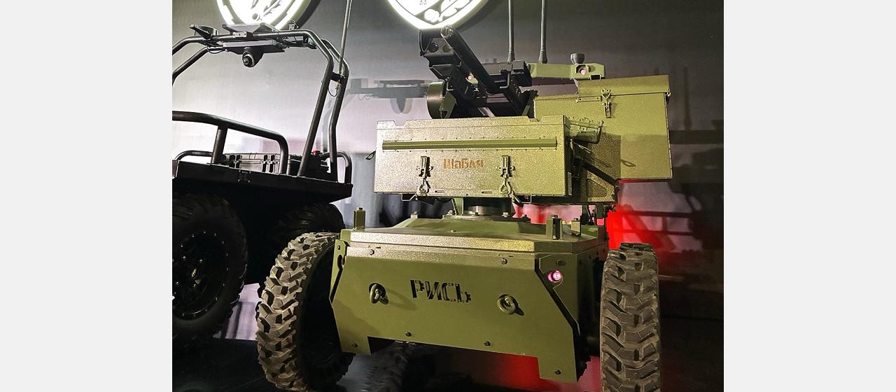 Ein militärisches Kettenfahrzeug mit Geschütz steht in einer Ausstellung.