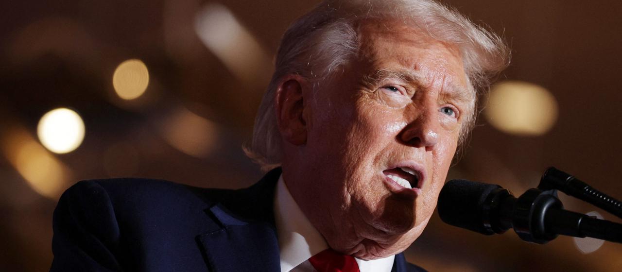 Donald Trump spricht in ein Mikrofon.