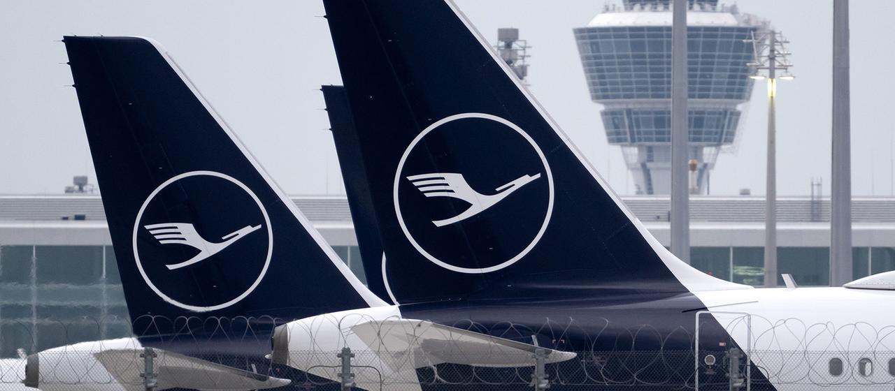 Flugzeuge der Lufthansa stehen an einem Flughafen.