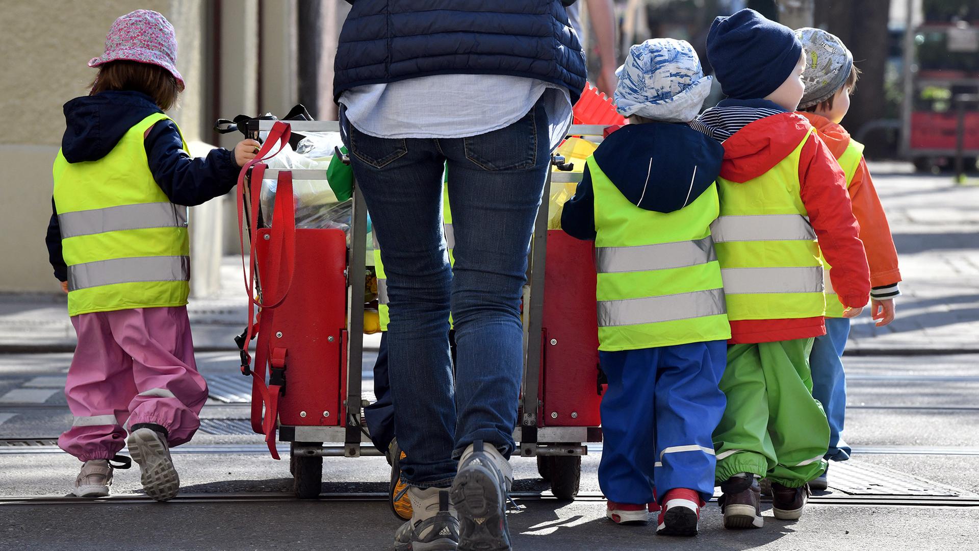 Ein Betreuerin läuft mit mehreren Kleinkindern über einen Bürgersteig. | Peter Kneffel/Deutsche Presse-Ag