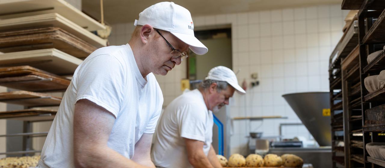 Zwei Bäcker arbeiten in einer Backstube.