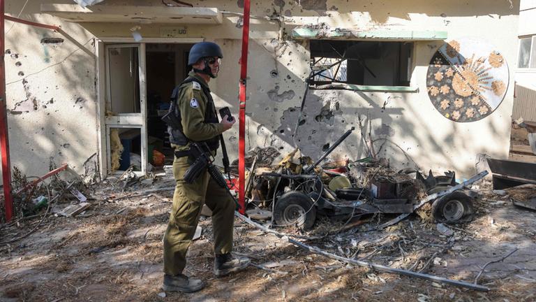 Ein israelischer Soldat läuft an abgebrannten Häusern im Kibbuz Beeri vorbei.