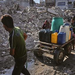 Palästinenser transportieren Wasser auf einem Karren inmitten der Ruinen von Gaza-Stadt.