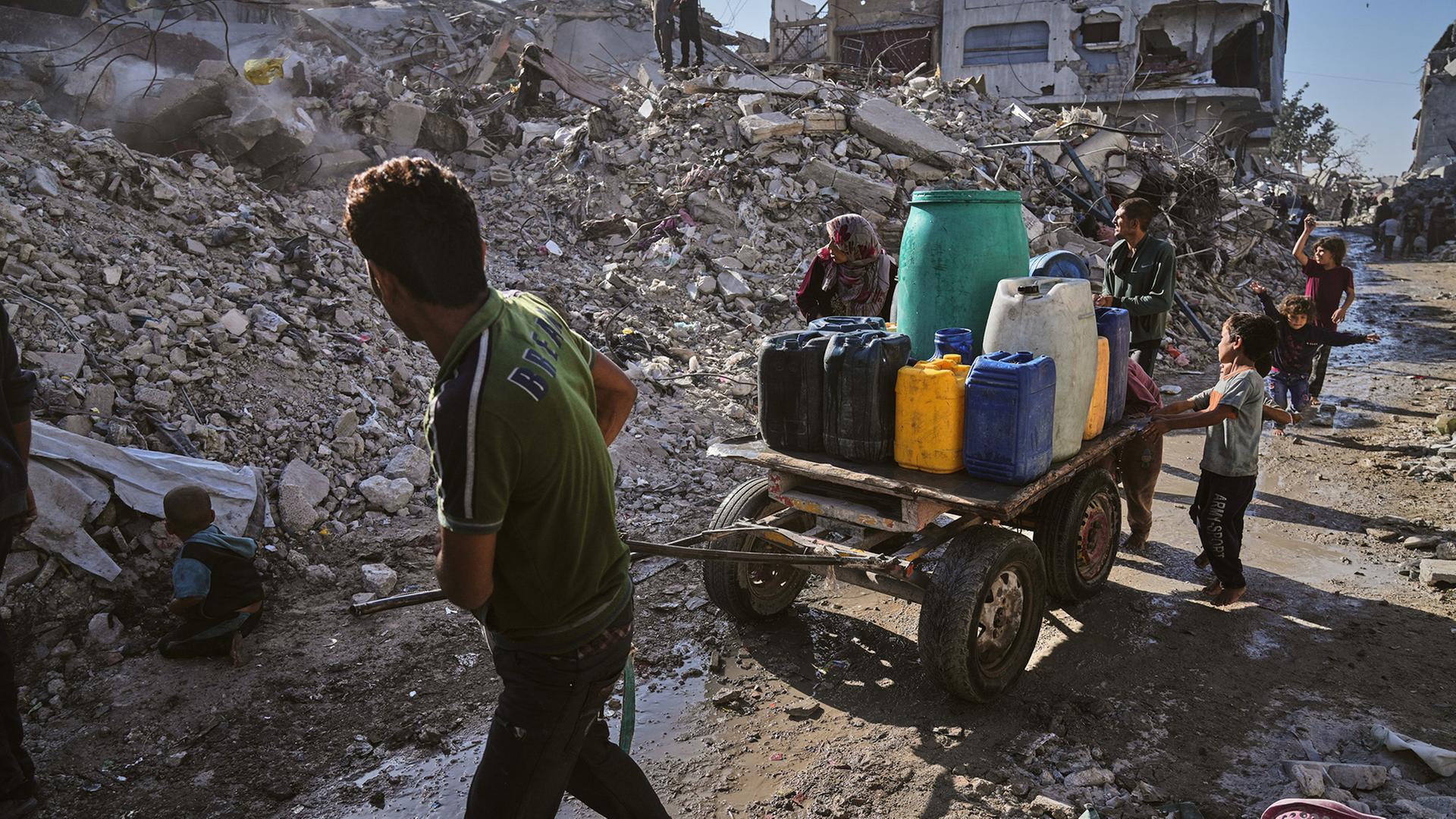 Palästinenser transportieren Wasser auf einem Karren inmitten der Ruinen von Gaza-Stadt. | AP
