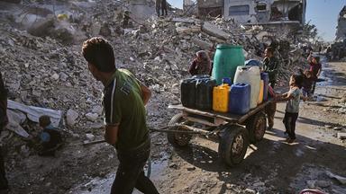 Palästinenser transportieren Wasser auf einem Karren inmitten der Ruinen von Gaza-Stadt.