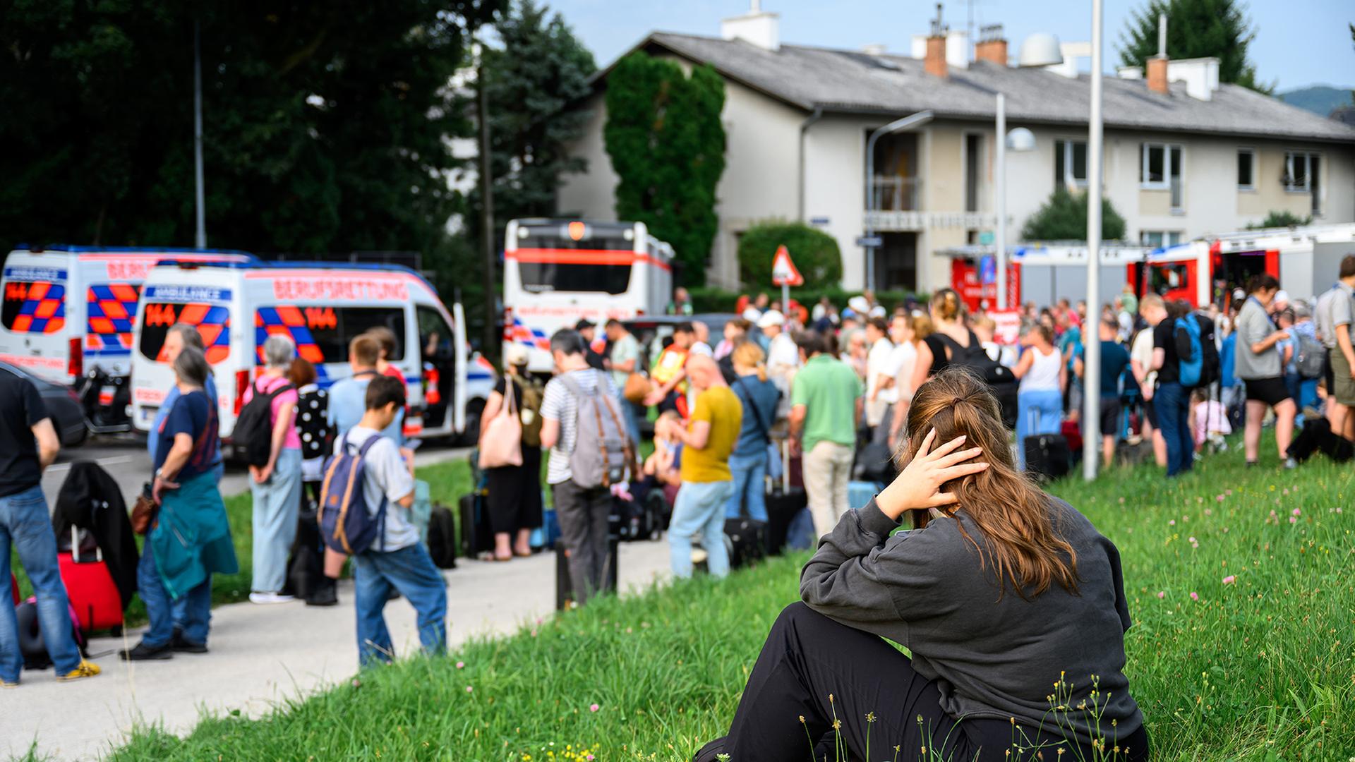 Zahlreiche Menschen stehen an einem Sammelplatz vor einem Bahnhof in  Österreich. | dpa