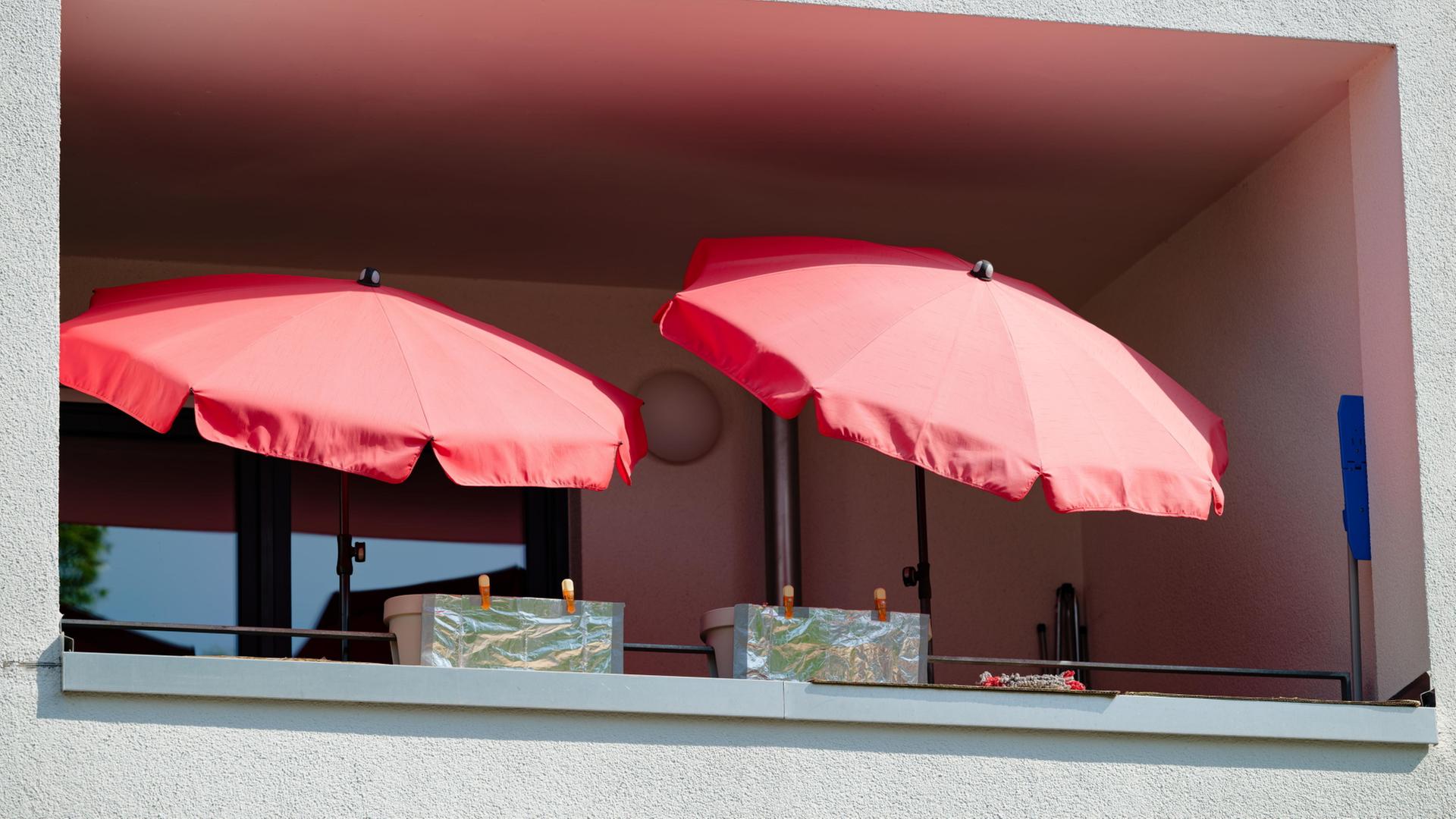 Sonnenschirme stehen auf einem Balkon. | dpa