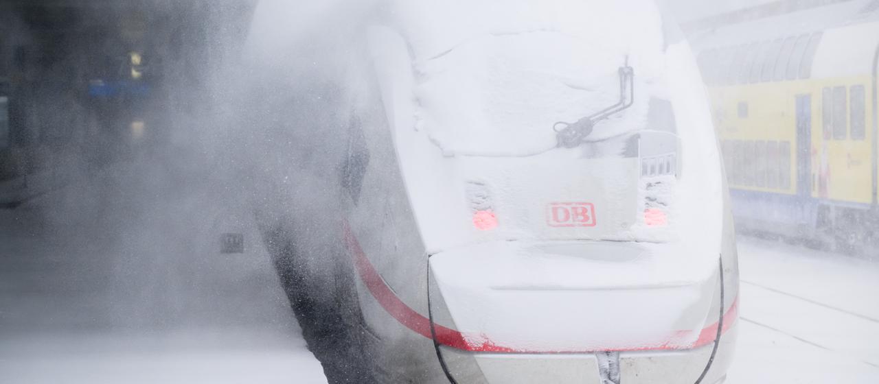 Ein ICE steht an einem Bahnsteig in einer Schneewolke.