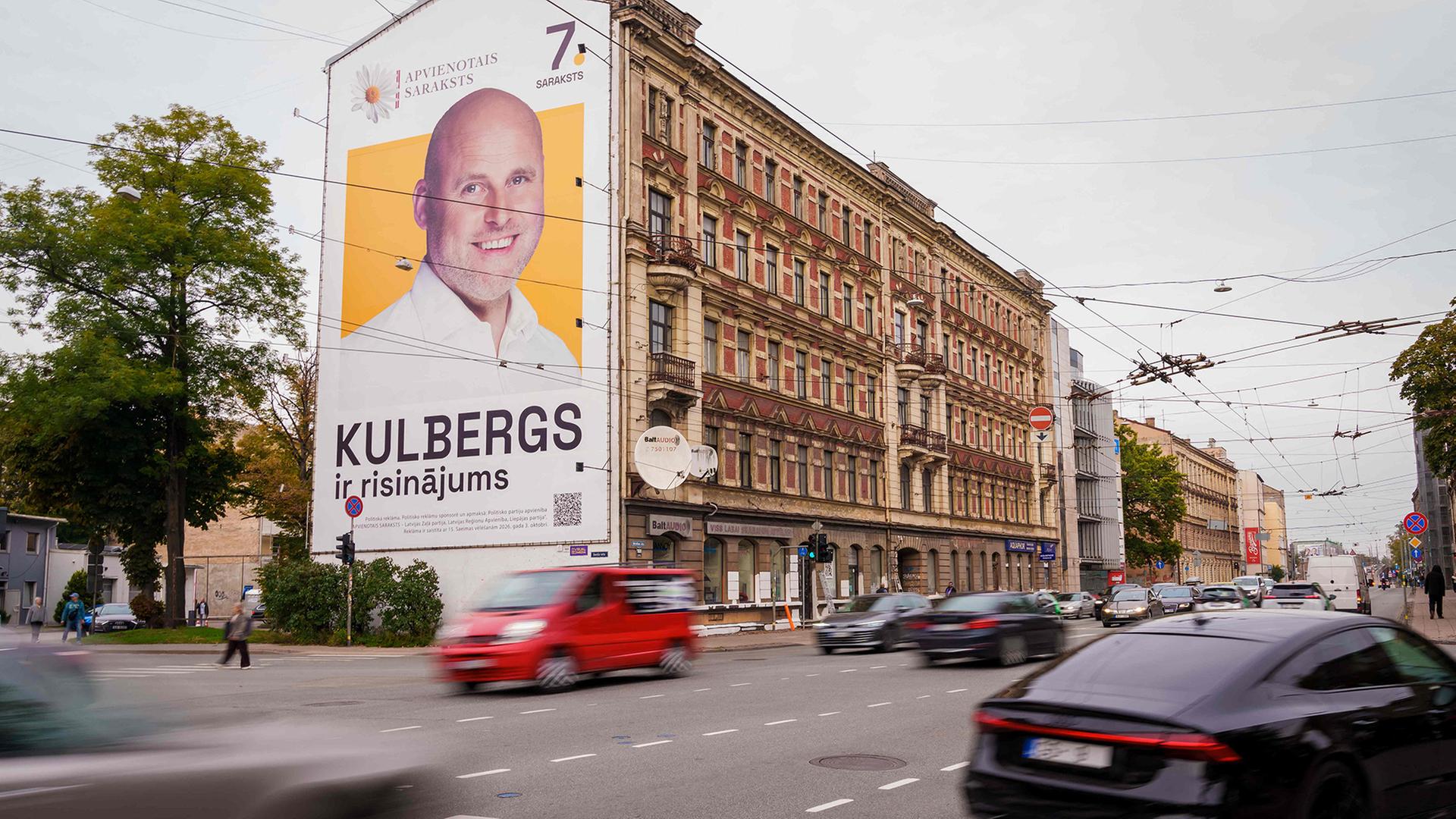 An einer Hauswand hängt ein Wahlplakat von Andris Kulbergs. | AFP