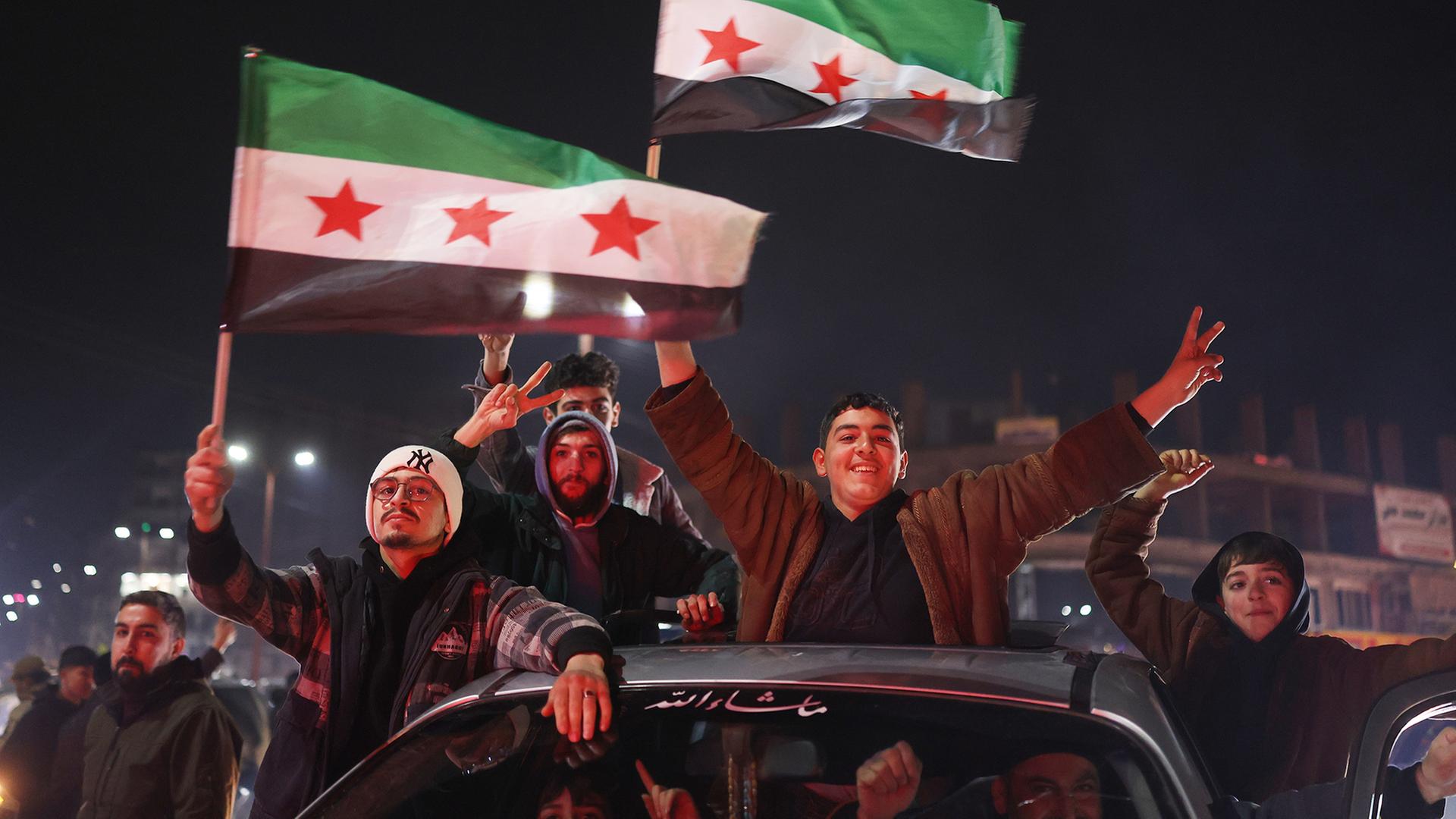 Menschen feiern mit syrischen Flaggen. | dpa