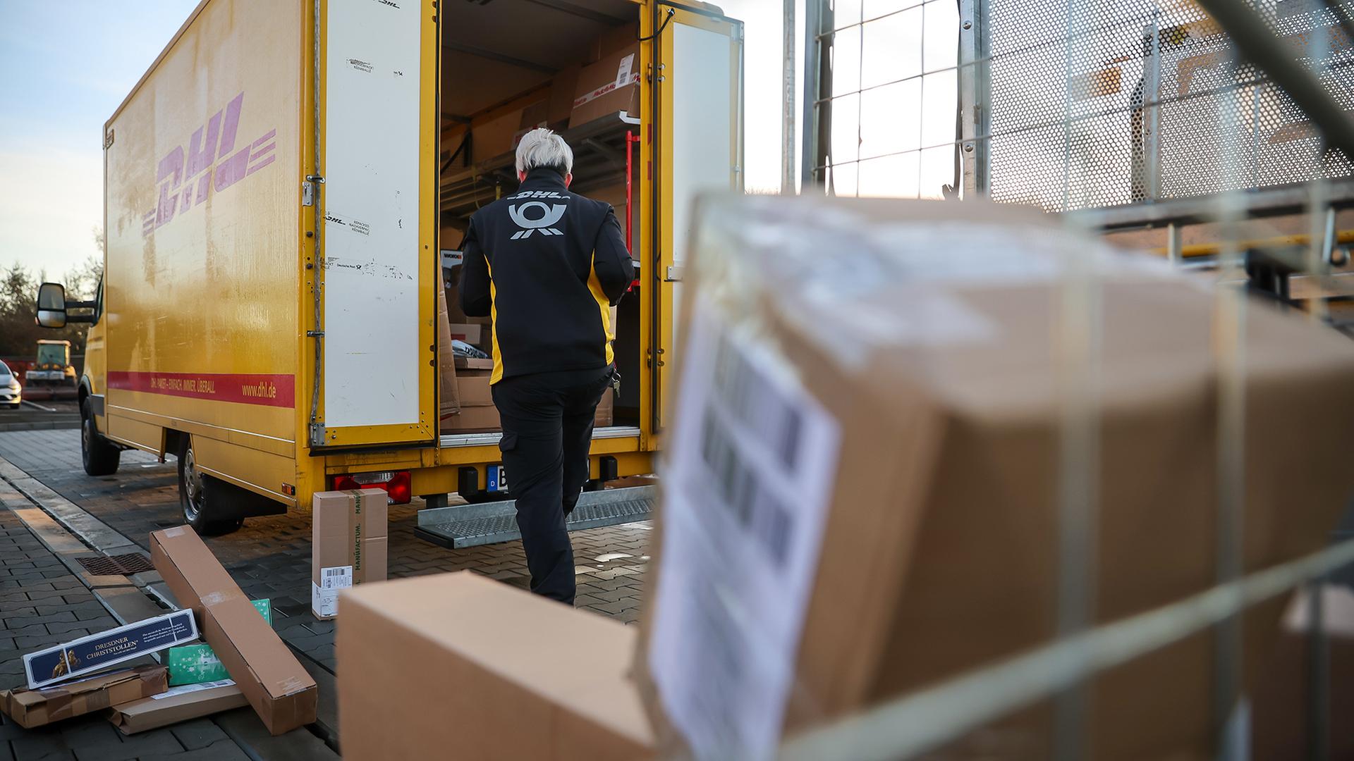 Eine Mitarbeiterin der Deutsche Post DHL bel�dt ihr Fahrzeug mit P�ckchen und Paketen. | dpa