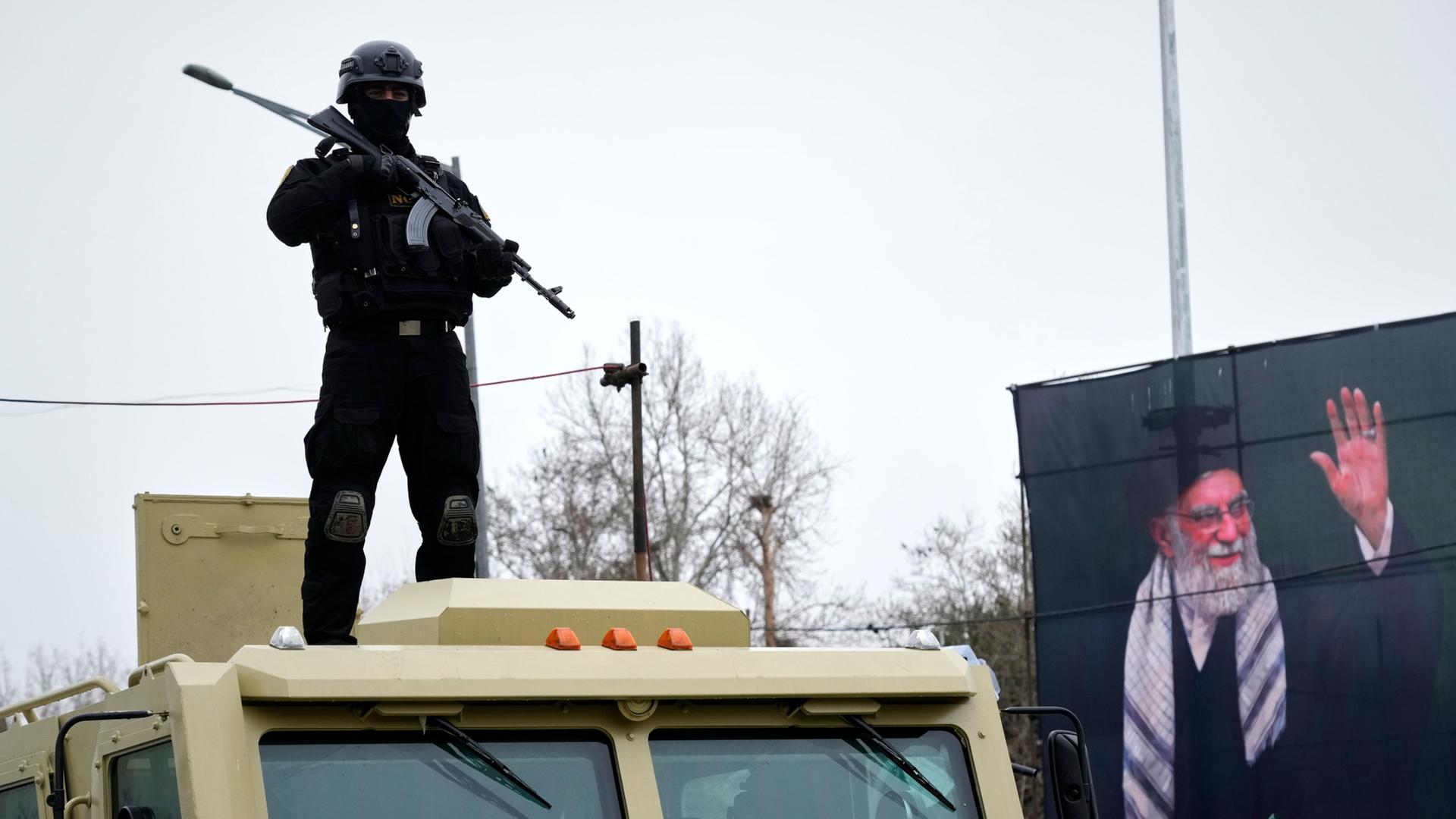 Ein Polizist steht neben einem Porträt des verstorbenen Ali Chamenei in Teheran | Vahid Salemi/AP/dpa
