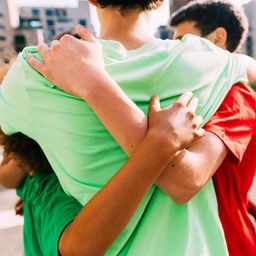 Freunde stehen in einer Gruppe und umarmen sich.