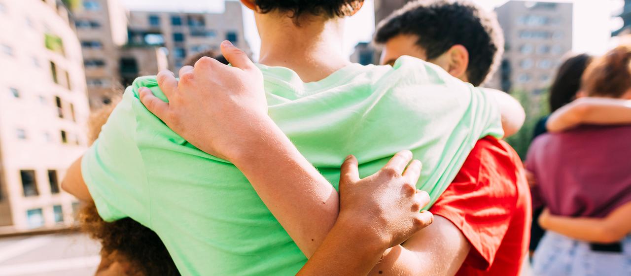 Freunde stehen in einer Gruppe und umarmen sich.