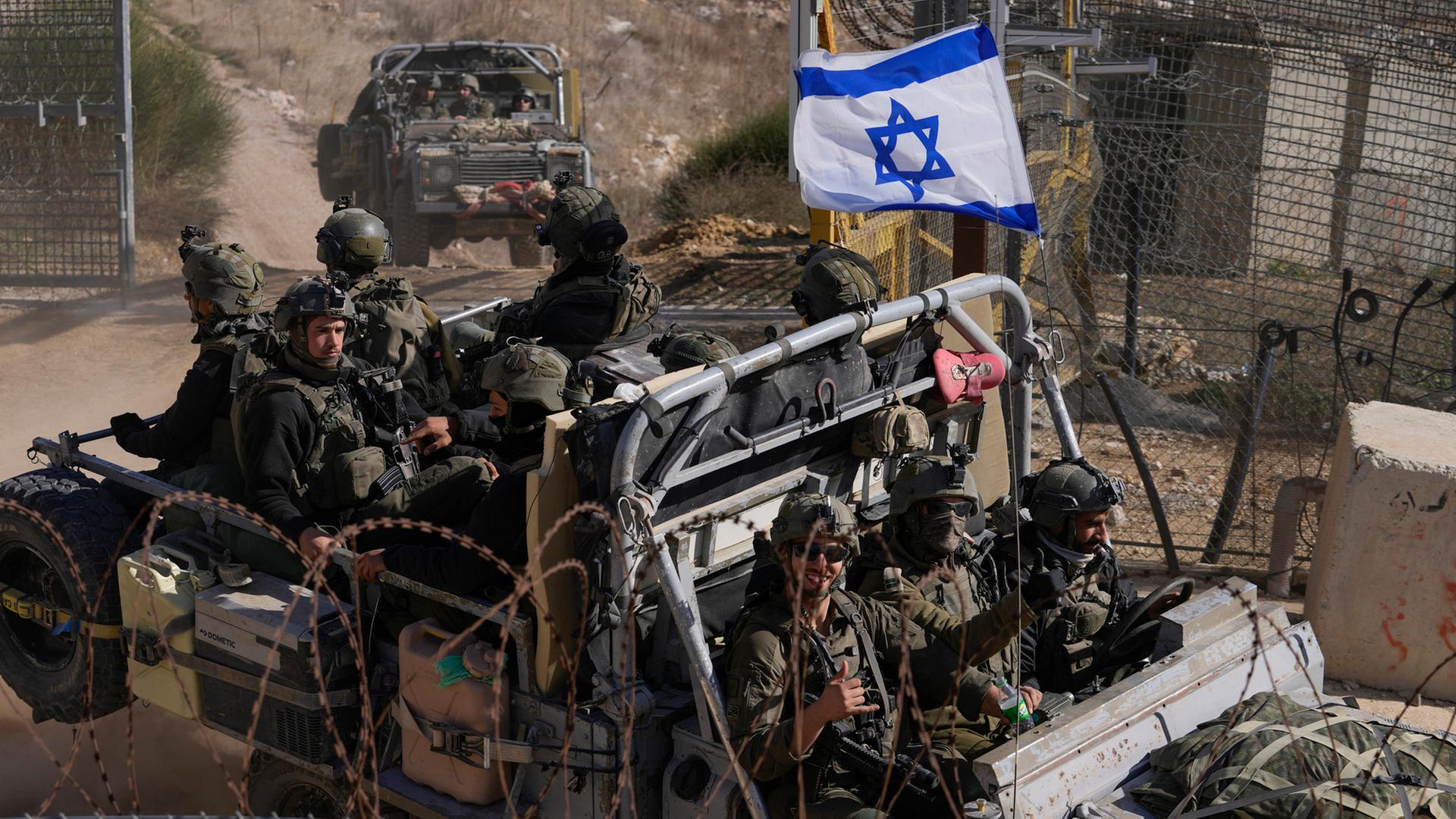 Israelische Soldaten mit der Nationalflagge stehen auf einem gepanzerten Fahrzeug. | AP
