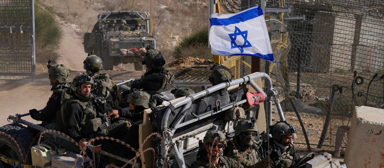 Israelische Soldaten mit der Nationalflagge stehen auf einem gepanzerten Fahrzeug.