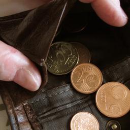 Eine Frau hält eine nahezu leere Geldbörse in den Händen