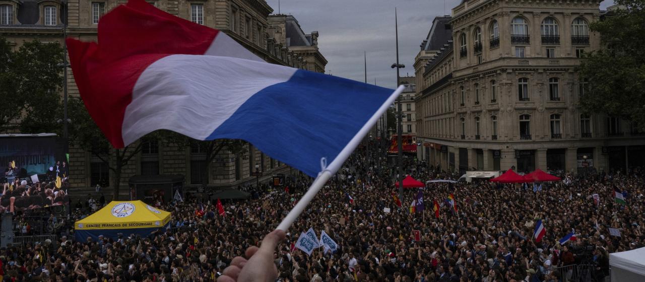 Jemand schwenkt eine französische Flagge bei einer Kundgebung.