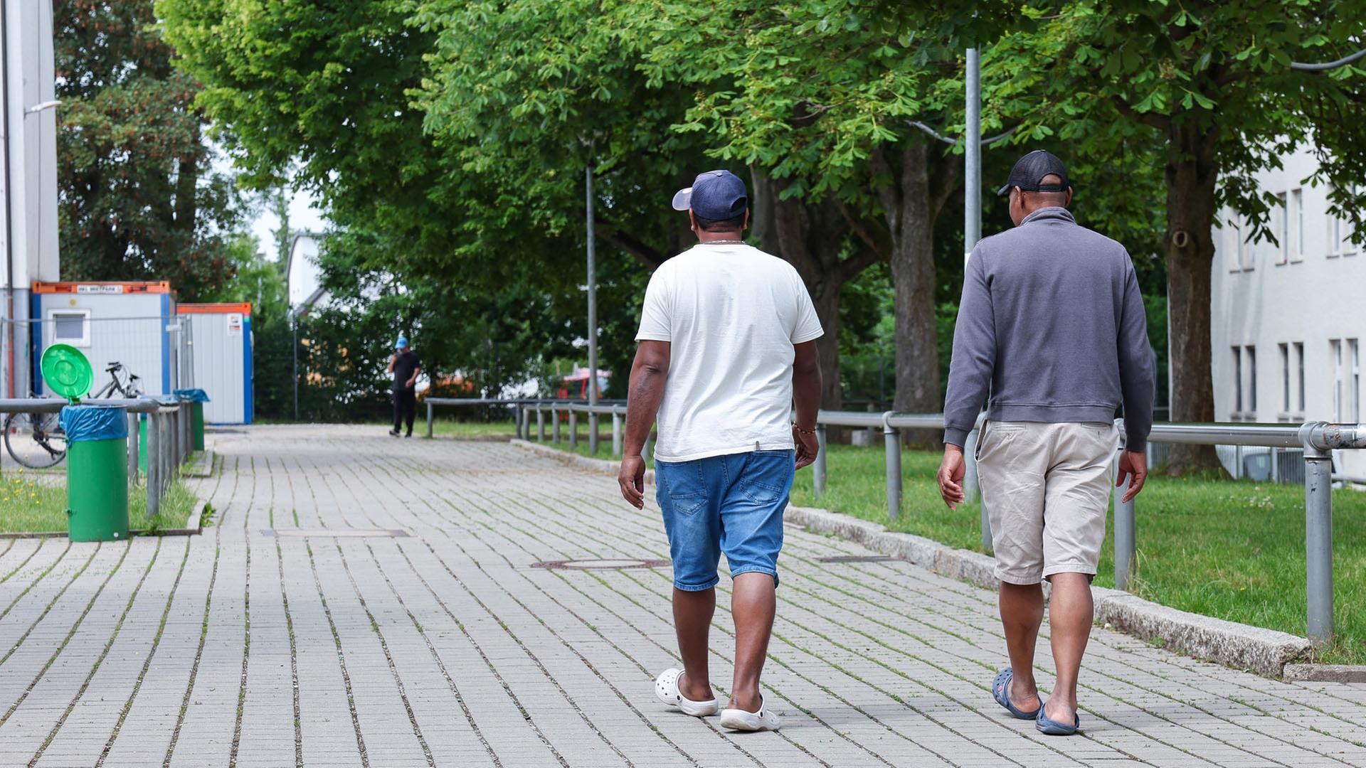 Zwei Bewohner gehen in der Zentralen Aufnahmeeinrichtung für Asylbewerber in Bayern über das Gelände. | picture alliance/dpa