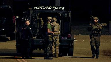 Polizisten vor einem Einsatzfahrzeug