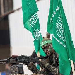 Ein Mitglieder der Al-Qasam Brigade steht mit Waffe zwischen Hamas-Fahnen.