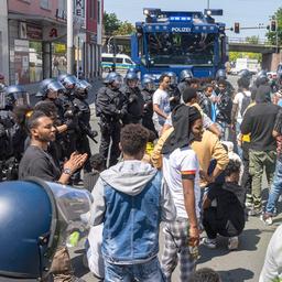 Polizisten haben eine Gruppe von Menschen umringt und im Hintergrund steht ein Wasserwerfer bereit