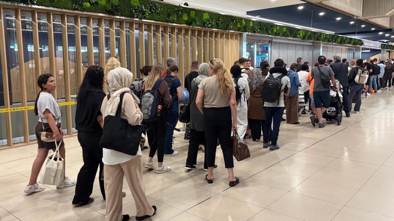 Eine Gruppe von Menschen wartet in einer Warteschlange am Flughafen