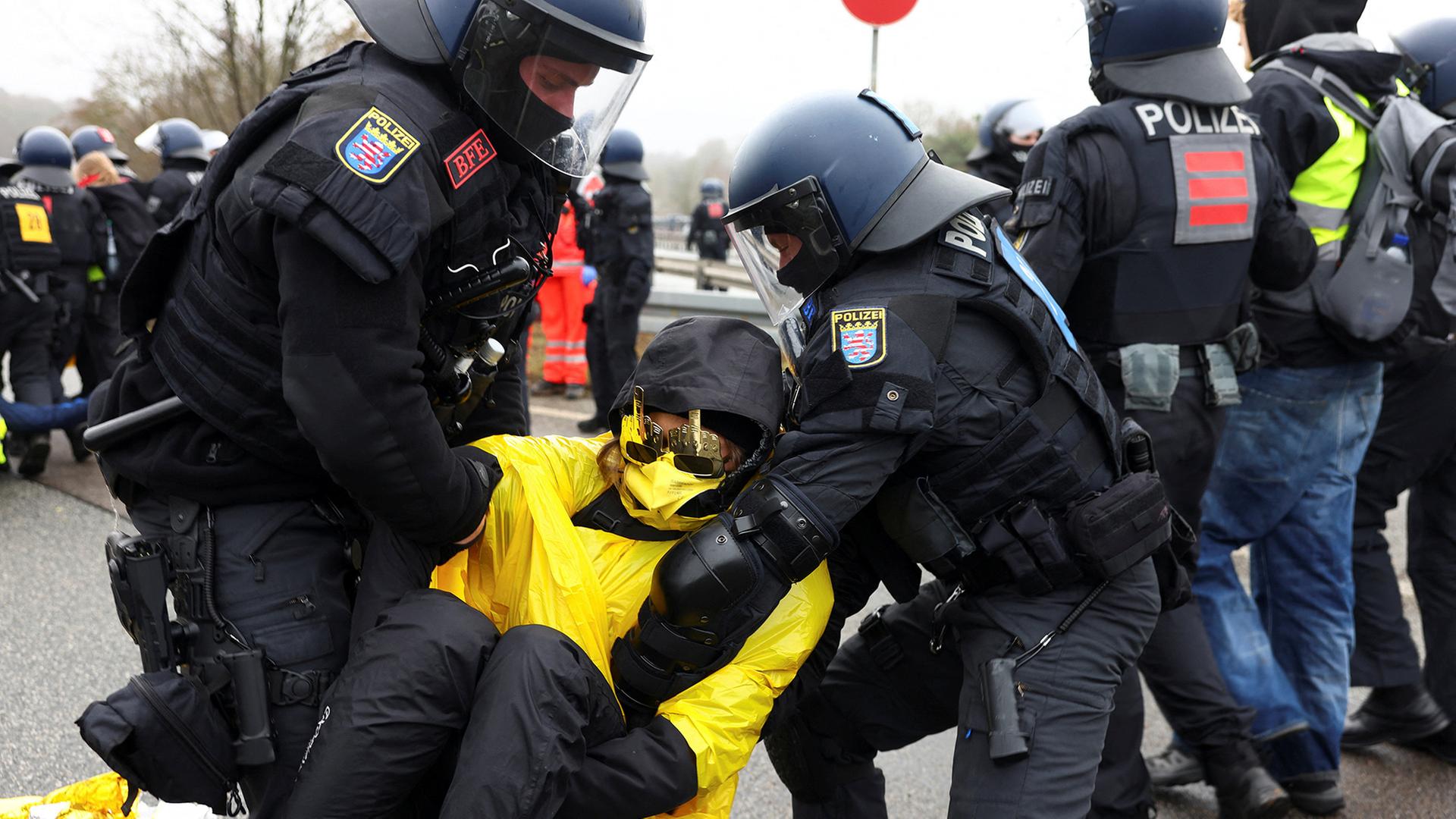 Polizeibeamte tragen einen Demonstranten von der Straße. | REUTERS