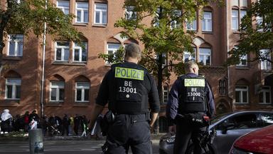 Polizisten stehen vor einem Gymnasium im Berliner Stadtteil Neukölln.