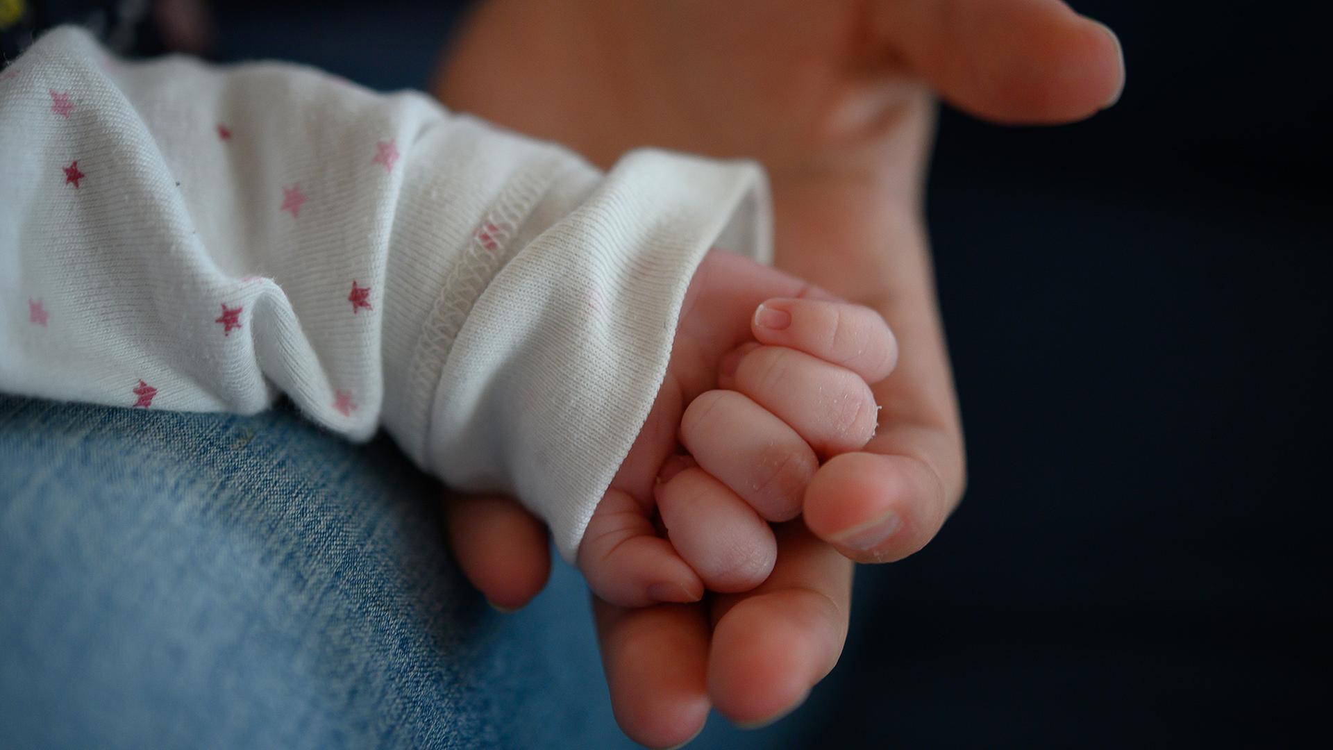 Die Hand eines Neugeborenen liegt in der Hand der Mutter | dpa