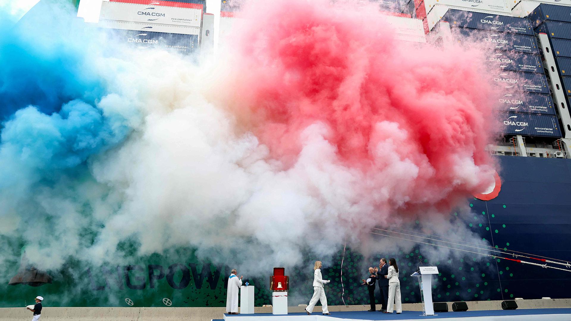 Bei der Taufe eines Containerschiffs sind bunte Rauchschwaden zu sehen. | AFP