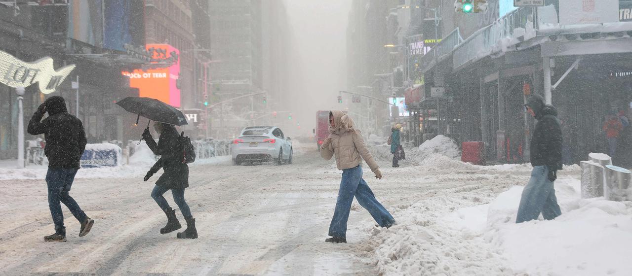 Menschen gehen in New York City während eines Schneesturms die Broadway in Times Square entlang.