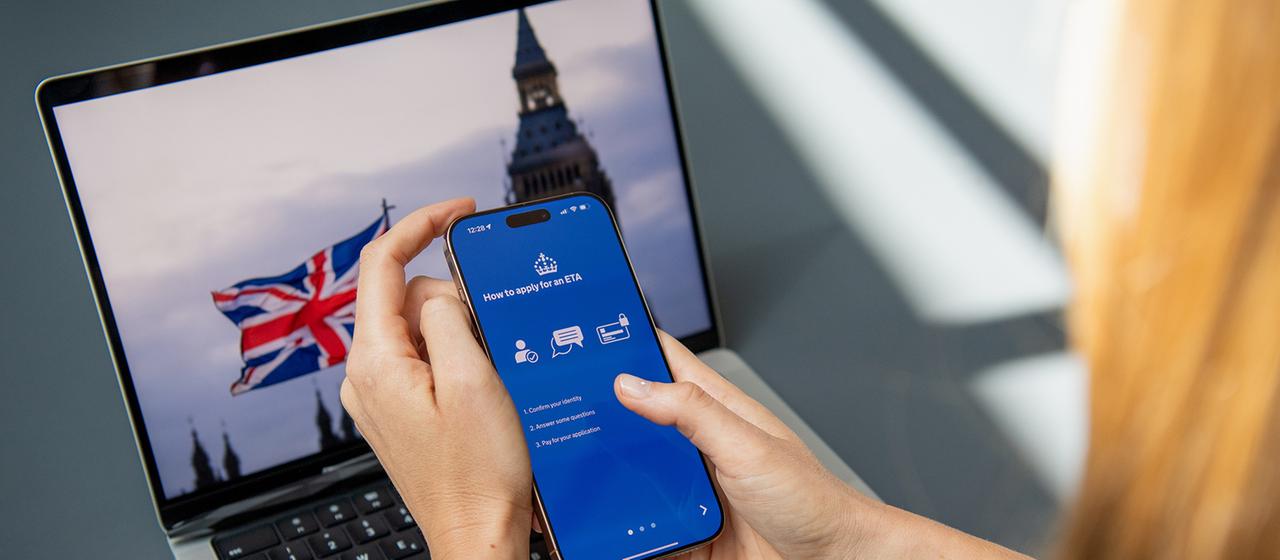 Eine Frau nutzt eine App auf ihrem Handy, um einen ETA-Antrag zu stellen.