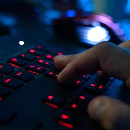 Ein Mann tippt auf einer rot beleuchteten Tastatur.