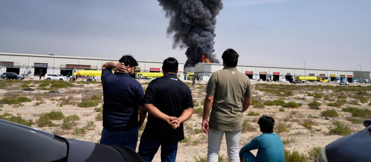 Anwohner beobachten, wie Flammen und eine schwarze Rauchwolke aus einem Lagerhaus im Industriegebiet von Sharjah City in den Vereinigten Arabischen Emiraten aufsteigen.