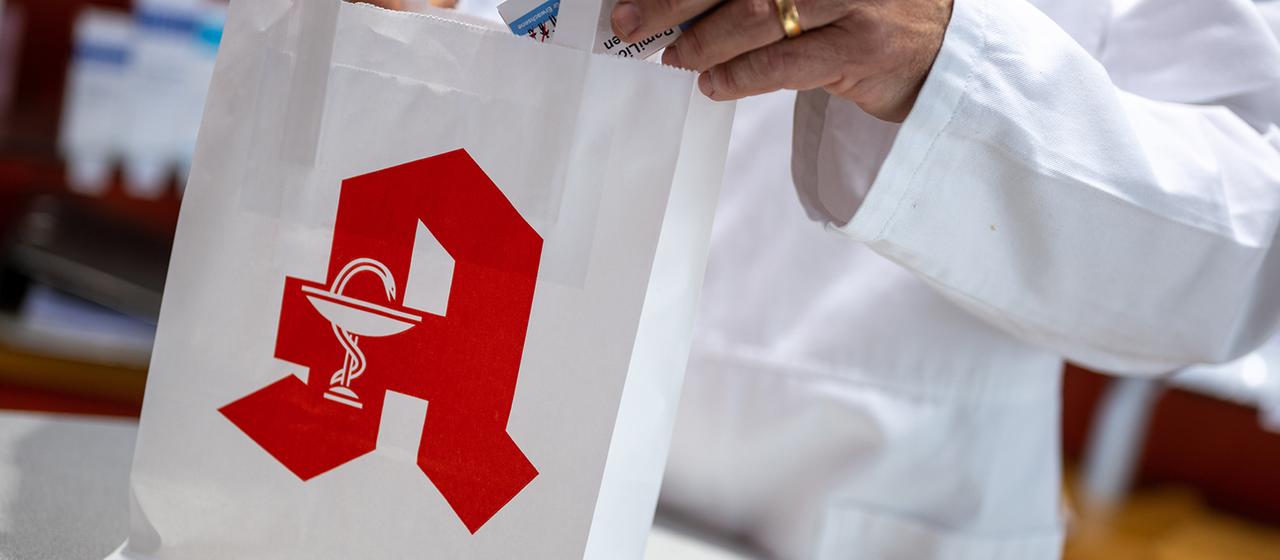 Ein Apotheker legt in einer Apotheke eine Packung mit Tabletten in eine Papiertasche mit Apotheken-Logo. | dpa Ein Apotheker legt in einer Apotheke eine Packung mit Tabletten in eine Papiertasche mit Apotheken-Logo.