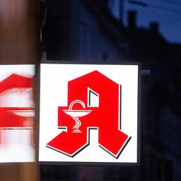 Ein Apothekenschild leuchtet an der Fassade eines Gebäudes.