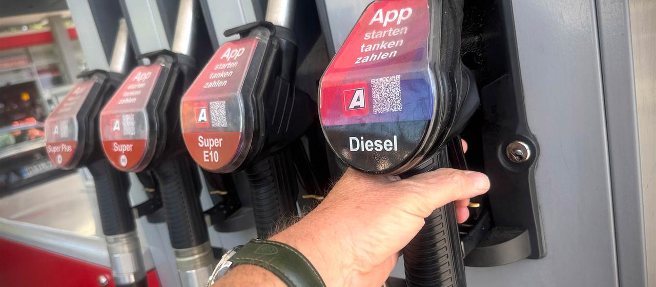 Eine Person greift nach einer Diesel-Zapfpistole an einer Tankstelle.