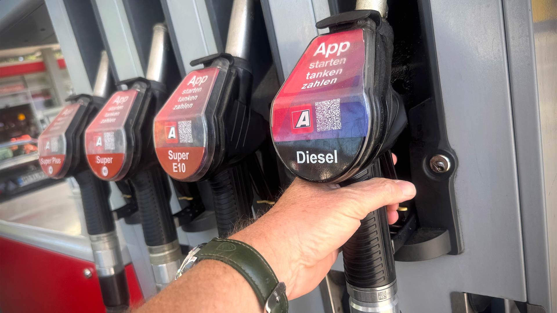 Eine Person greift nach einer Diesel-Zapfpistole an einer Tankstelle. | picture alliance / SvenSimon