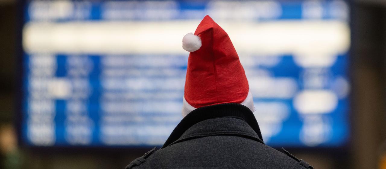 Ein Mann mit Weihnachtsmannmütze in einem Banhof | picture alliance/dpa Ein Mann mit Weihnachtsmannmütze in einem Banhof