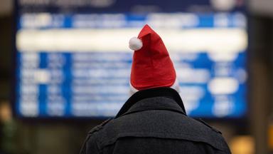 Ein Mann mit Weihnachtsmannmütze in einem Banhof