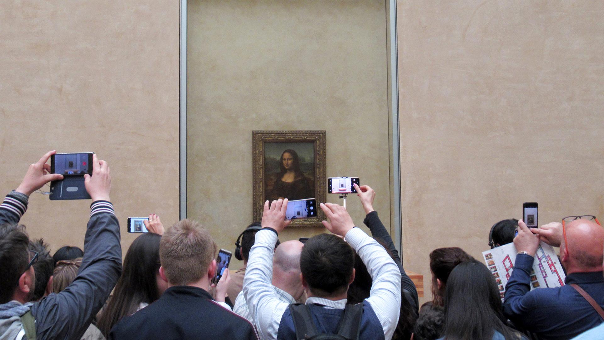 Besucher stehen mit ihren Handys und Smartphones vor der 