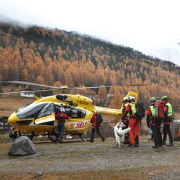 Mitglieder der Bergrettung sammeln sich vor einem Rettungshubschrauber.