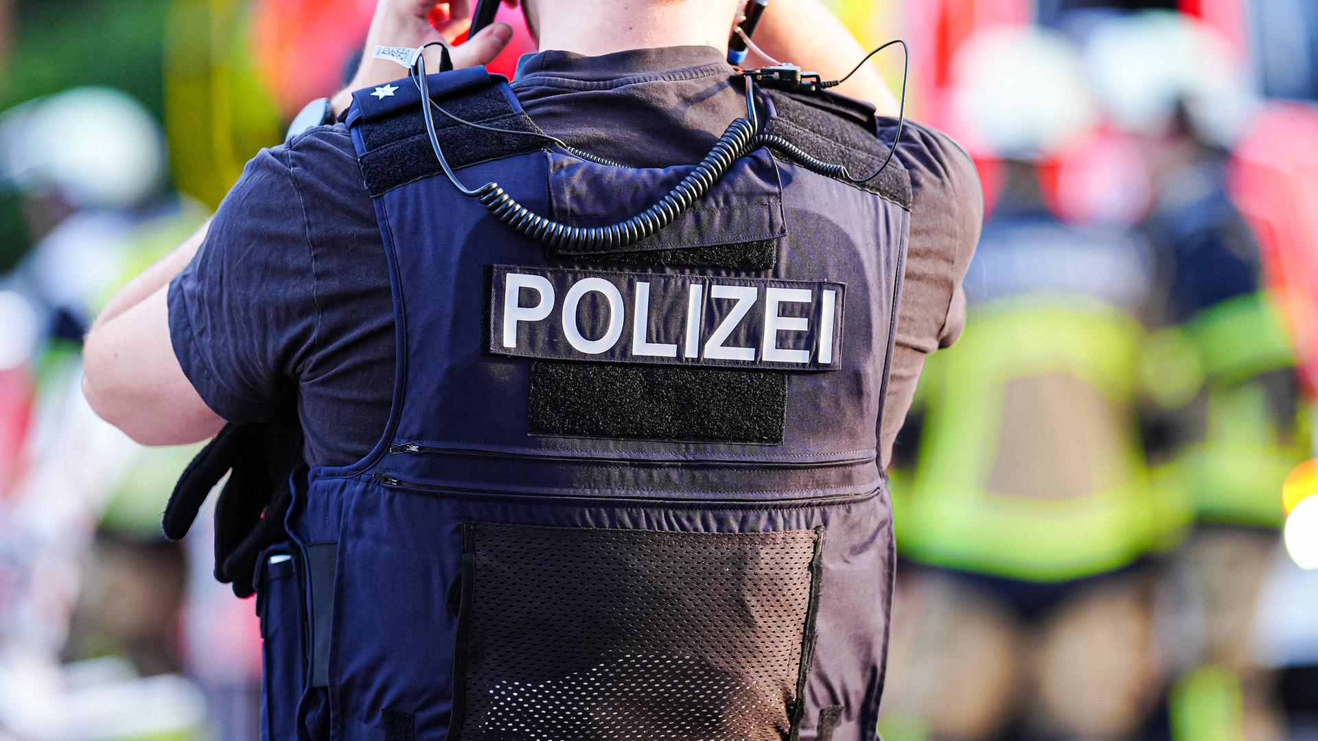 So könnte es auch in Bremen aussehen: Ein Polizist in Bargteheide mit einer kugelsicheren Weste, im Hintergrund sind Mitglieder der Feuerwehr zu sehen. | Imago | Eibner