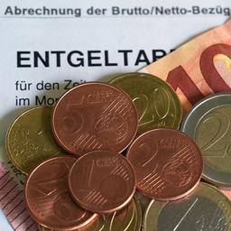 Euro- und Centmünzen liegen auf einem 10-Euro-Schein und einer Entgeltabrechnung.